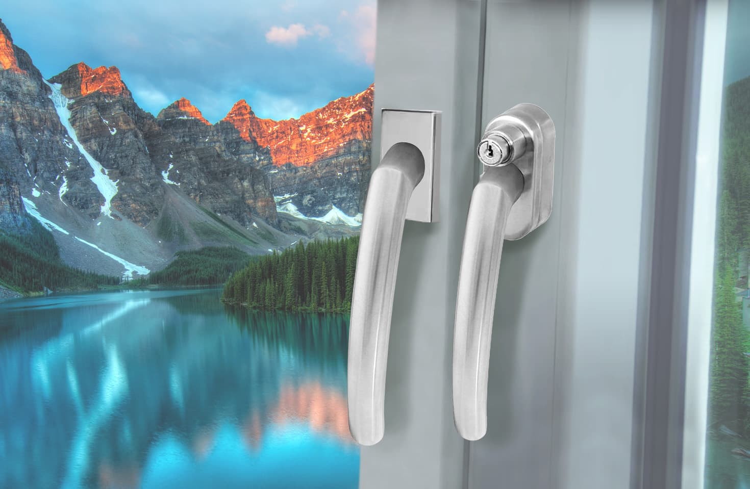 Zwei Fenstergriffe, einer davon abschließbar, an einem Fenster vor einer Berglandschaft